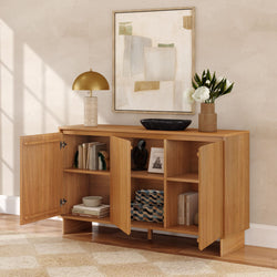 Oak sideboard storage cabinet with open doors and shelves, modern gold table lamp, abstract framed art, black bowl and vase of white peonies in a neutral living room