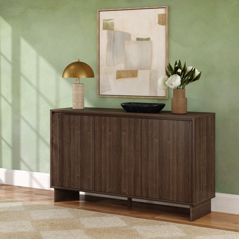 Dark walnut mid-century modern console cabinet and storage sideboard against sage green wall with abstract framed art, gold table lamp, black decorative bowl and vase of white peonies on hardwood floor