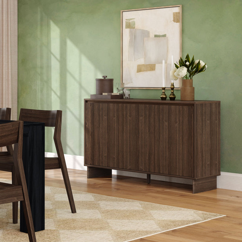 Dark walnut mid-century modern sideboard credenza in dining room with green accent wall, abstract wall art, brass candlesticks and white floral vase