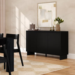 Modern black sideboard in minimalist dining room with wood floors, abstract wall art, vase of white flowers and brass candlesticks.