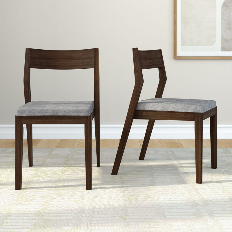 Contemporary wooden dining chairs with grey cushions on a light carpet in a modern living room.