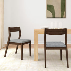 Modern dining room with wooden table and gray upholstered chairs, featuring minimalist art on the wall.