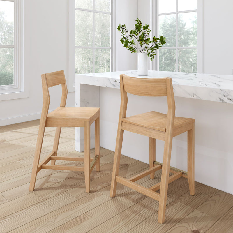 Modern wooden bar stools at a white marble kitchen counter in a bright room with large windows.