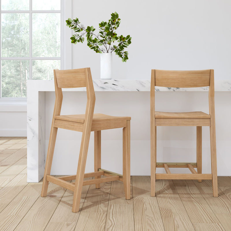 Wooden bar stools in a modern kitchen with white marble countertop and decorative plant.