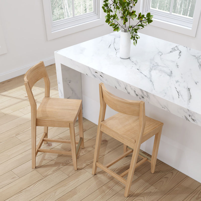 Wooden bar stools next to a white marble countertop in a modern kitchen with light wood flooring.