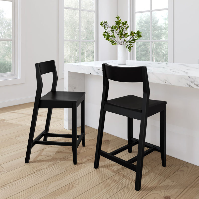 Modern black bar stools in a bright kitchen with a marble countertop and white vase with greenery.