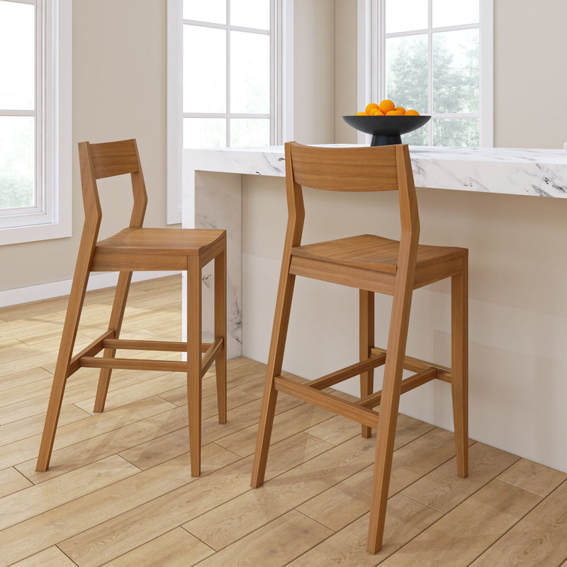 Modern bar stools with wooden design in a bright kitchen setting, featuring a white marble countertop and a bowl of oranges for decoration.