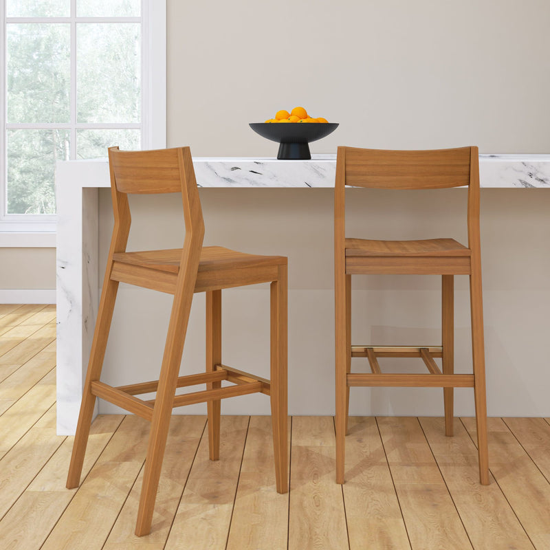 Wooden bar stools at a marble kitchen island with a bowl of oranges, wooden flooring, and a large window.
