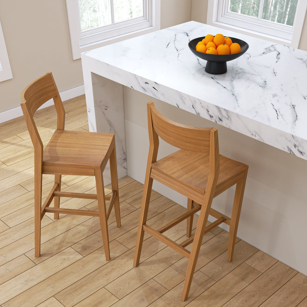 Wooden bar stools next to a marble kitchen island with a bowl of oranges.