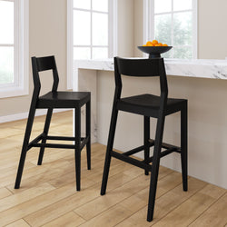 Modern black bar stools at a marble kitchen counter with a bowl of oranges.