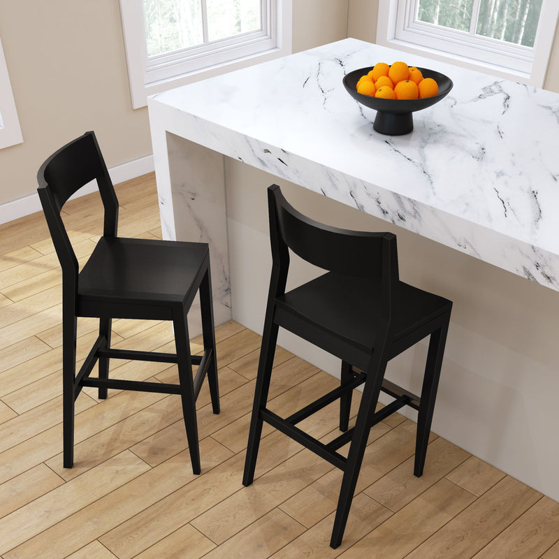 Black modern bar stools at a white marble kitchen island with a bowl of oranges.