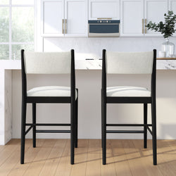 Pair of modern black-framed counter-height bar stools with white upholstered seats at a marble kitchen island in a bright white kitchen
