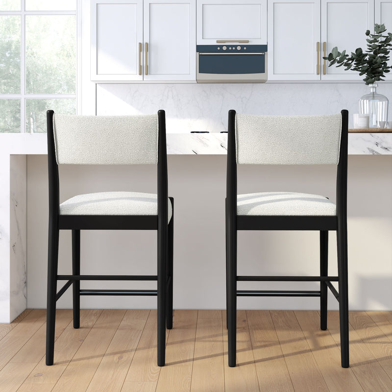 Pair of modern black-framed counter-height bar stools with white upholstered seats at a marble kitchen island in a bright white kitchen