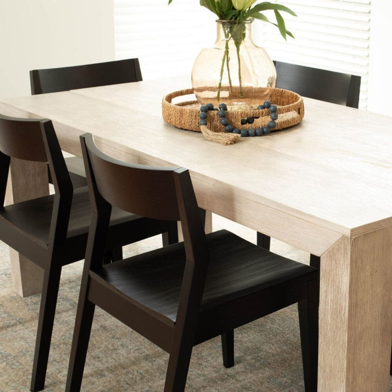 Modern dining room with light wood table, black chairs, and decorative centerpiece.