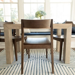 Modern dining room with wooden chairs, geometric rug, and hydrangea centerpiece in natural light.