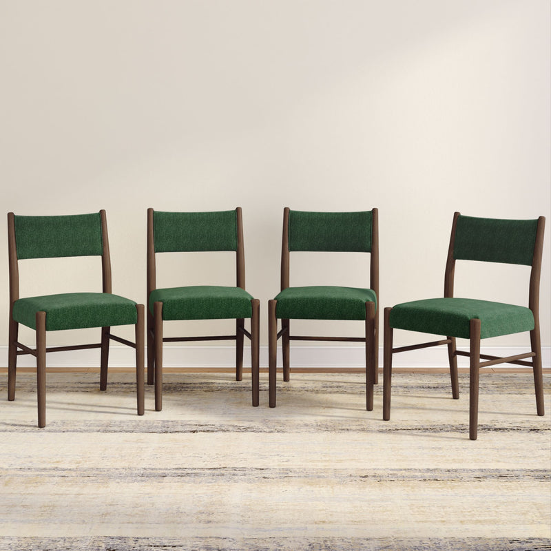 Set of four modern green upholstered dining chairs with wooden frames placed on a neutral rug.