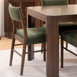 Modern dining room with dark wood table and green upholstered chairs on a beige carpet.