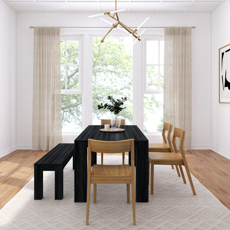 Modern minimalist dining room with black rectangular table, wooden chairs and bench, geometric pendant light, sheer curtains, large sunlit windows and hardwood floor