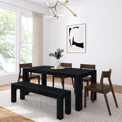 Modern black wood dining table and bench set with mid-century wooden chairs in a bright minimalist dining room featuring abstract wall art, gold chandelier, large window, and greenery centerpiece