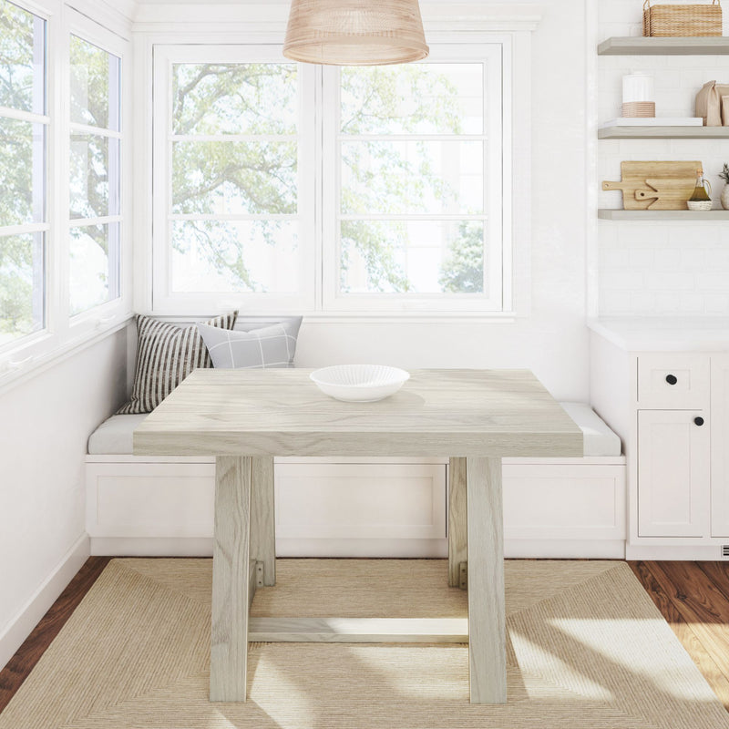 Bright modern farmhouse kitchen nook with window seat, light wood table, striped cushions, pendant lamp, open shelves and natural light