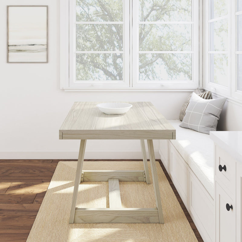 Bright minimalist dining nook with light wood table and white bowl, cozy built-in window seat with gray pillows and large white-framed windows