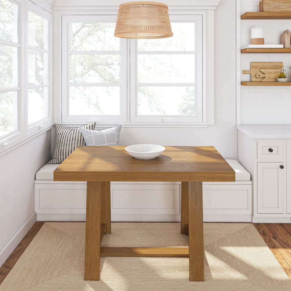 Cozy breakfast nook with wooden table, cushioned seating, and minimalist decor in sunny kitchen.