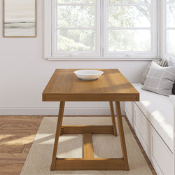 Modern wooden dining table with a white decorative bowl and gray cushions in a cozy sunlit room.