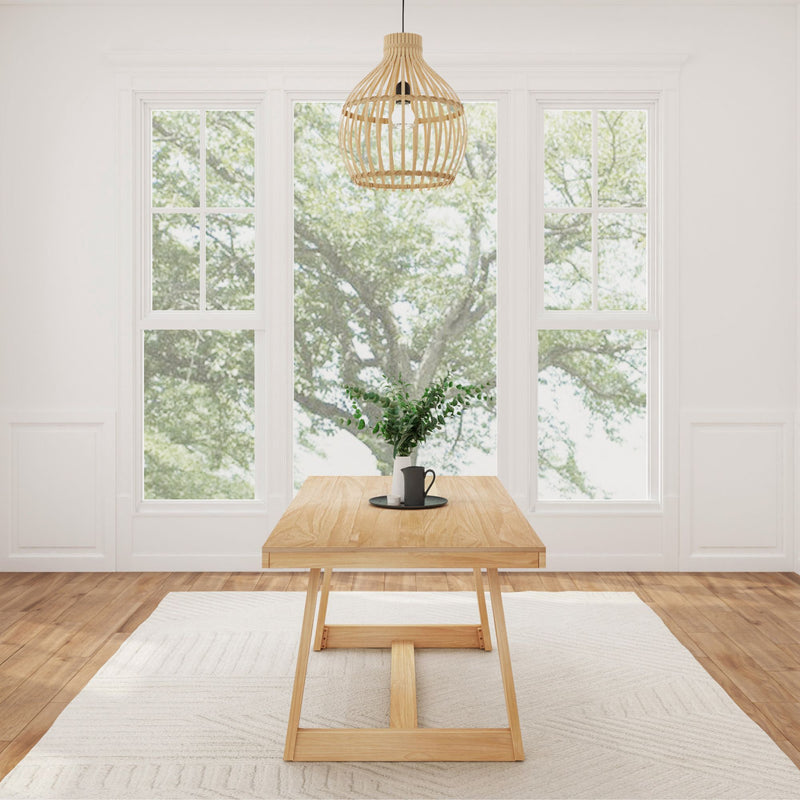 Contemporary dining room with wooden table, modern pendant light, and large windows showcasing a tree view.