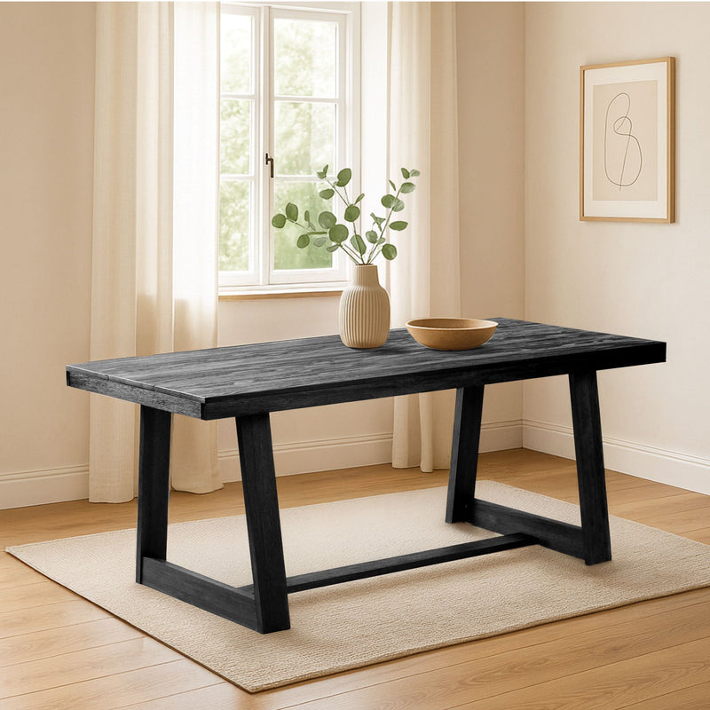Modern black wooden dining table in a bright minimalist room with decor and natural light.