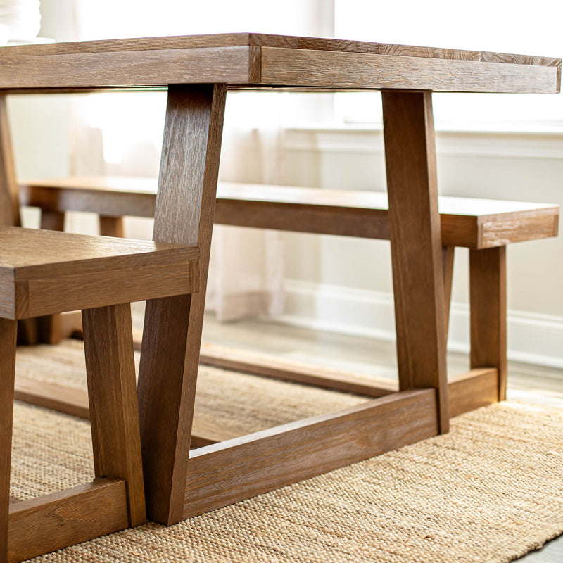 Wooden dining table and bench set on jute rug in modern dining room.