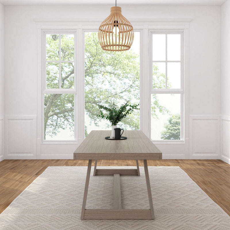 Minimalist Scandinavian dining room with light wood table, rattan pendant light, large windows flooding natural light, greenery centerpiece, hardwood floors and neutral rug