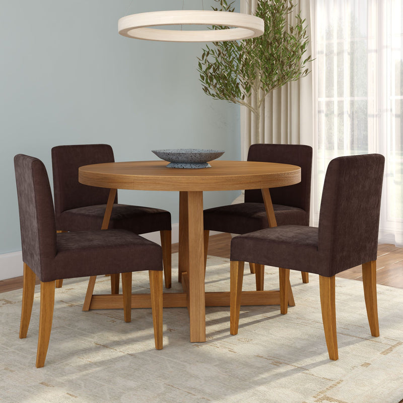 Round oak dining table with bowl centerpiece and four brown upholstered chairs in a sunlit contemporary dining room with pendant light, rug, and potted indoor tree