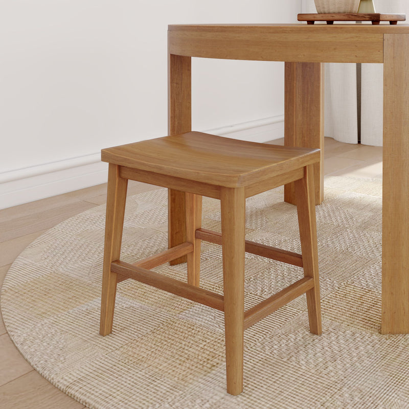 Wooden stool next to a dining table on a woven rug in a modern living space.