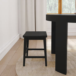 Modern black wooden dining stool beside a black dining table leg on a round woven jute rug over light hardwood floor in a minimalist sunlit dining nook with white curtains and a wooden-framed window