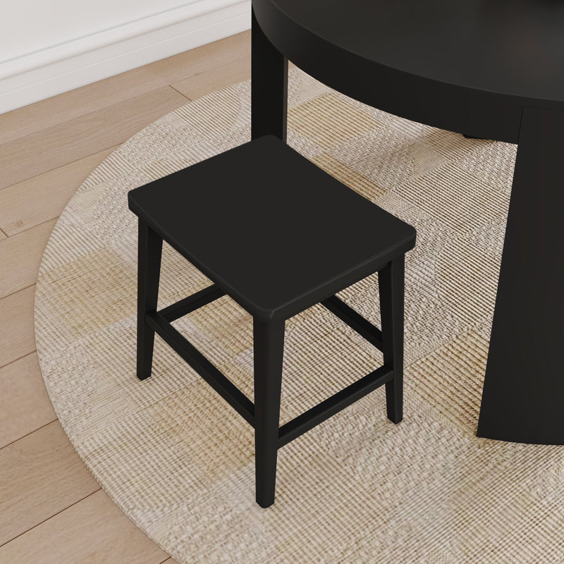 Black wooden stool next to a round black dining table on a beige textured rug over light hardwood floor, modern minimalist seating
