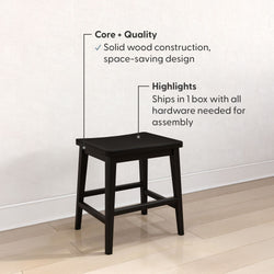 Black solid wood square stool on light hardwood floor against white wall — space-saving kitchen stool with crossbar supports, durable solid wood construction, ships in one box with hardware for easy assembly