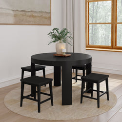 Modern black round dining table with four matching stools on a woven round rug in a bright minimalist dining room — compact space-saving kitchen table set for small apartments and modern homes
