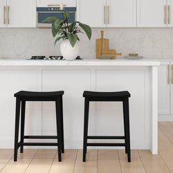 Black bar stools in a modern white kitchen with marble countertops and plant decor.