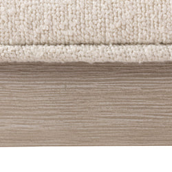 Cream textured upholstery on wooden furniture base close-up.