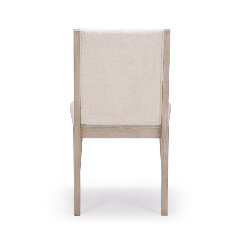 Back view of a modern beige upholstered dining chair with wooden frame.