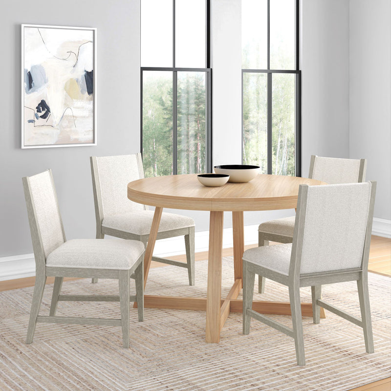 Round wooden dining table set with four upholstered chairs in a bright modern dining room.