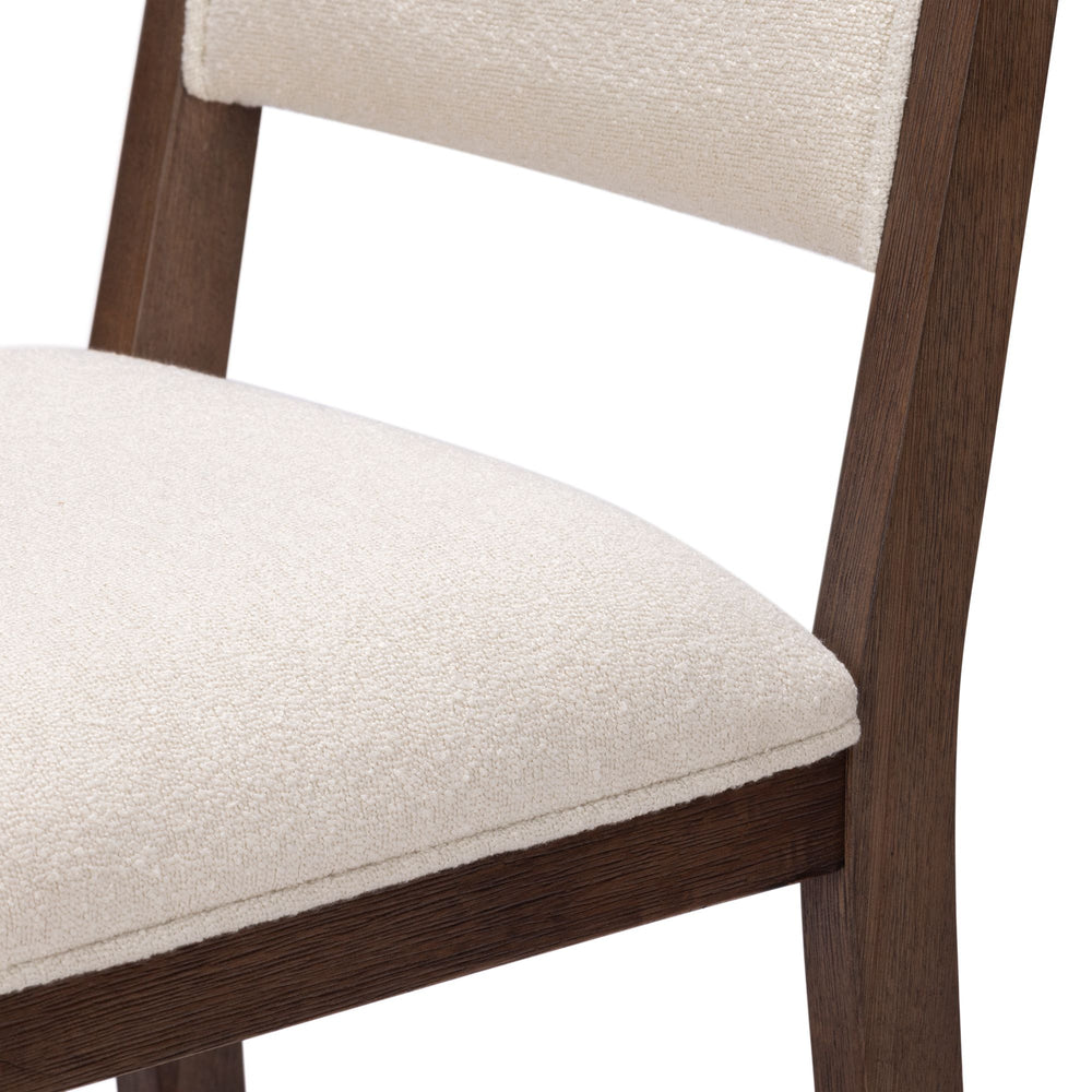 Wooden dining chair with white upholstered seat close-up.