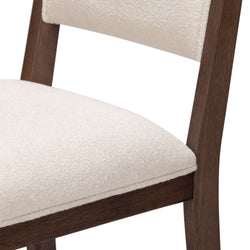 Wooden dining chair with white upholstered seat close-up.