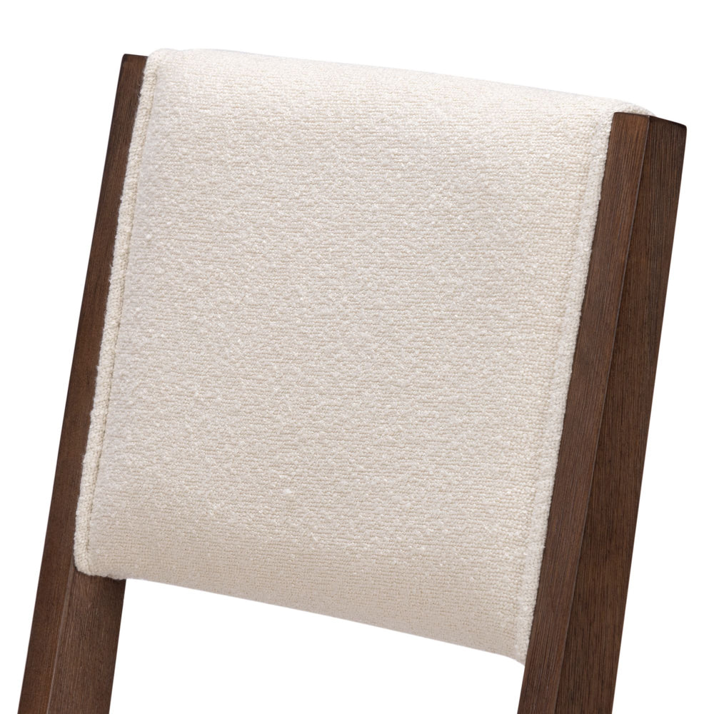 Cream fabric upholstered chair back with dark wood frame.