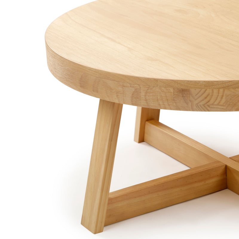 Round wooden coffee table with sturdy legs and a minimalist design.