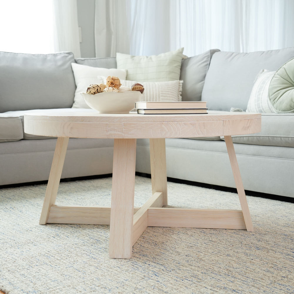 Modern light wood coffee table in a cozy living room with gray sofa and decorative cushions.