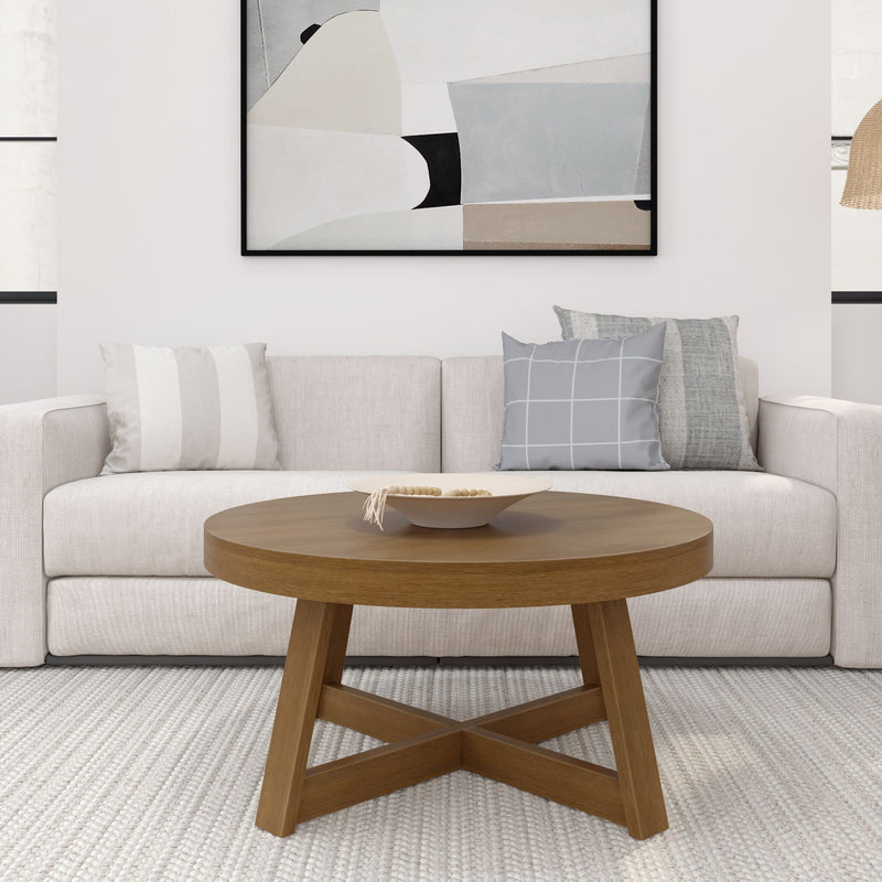Cozy modern neutral living room with beige sofa, round oak coffee table, gray patterned throw pillows and abstract wall art
