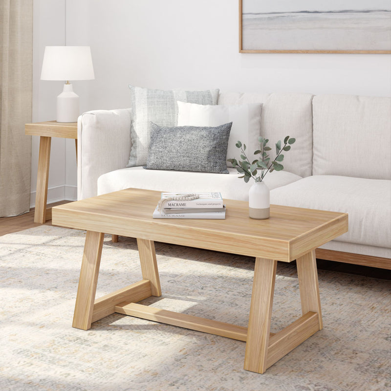Modern living room with minimalist wooden coffee table, cream sofa, and decorative vase on a light rug.