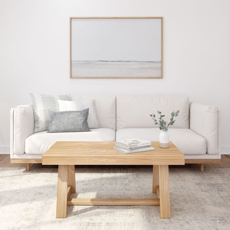 Minimalist living room with white sofa, wooden coffee table, and decorative plants.