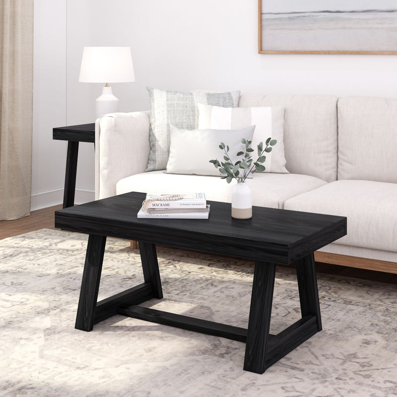 Modern black coffee table with books and decorative vase in stylish living room setting.